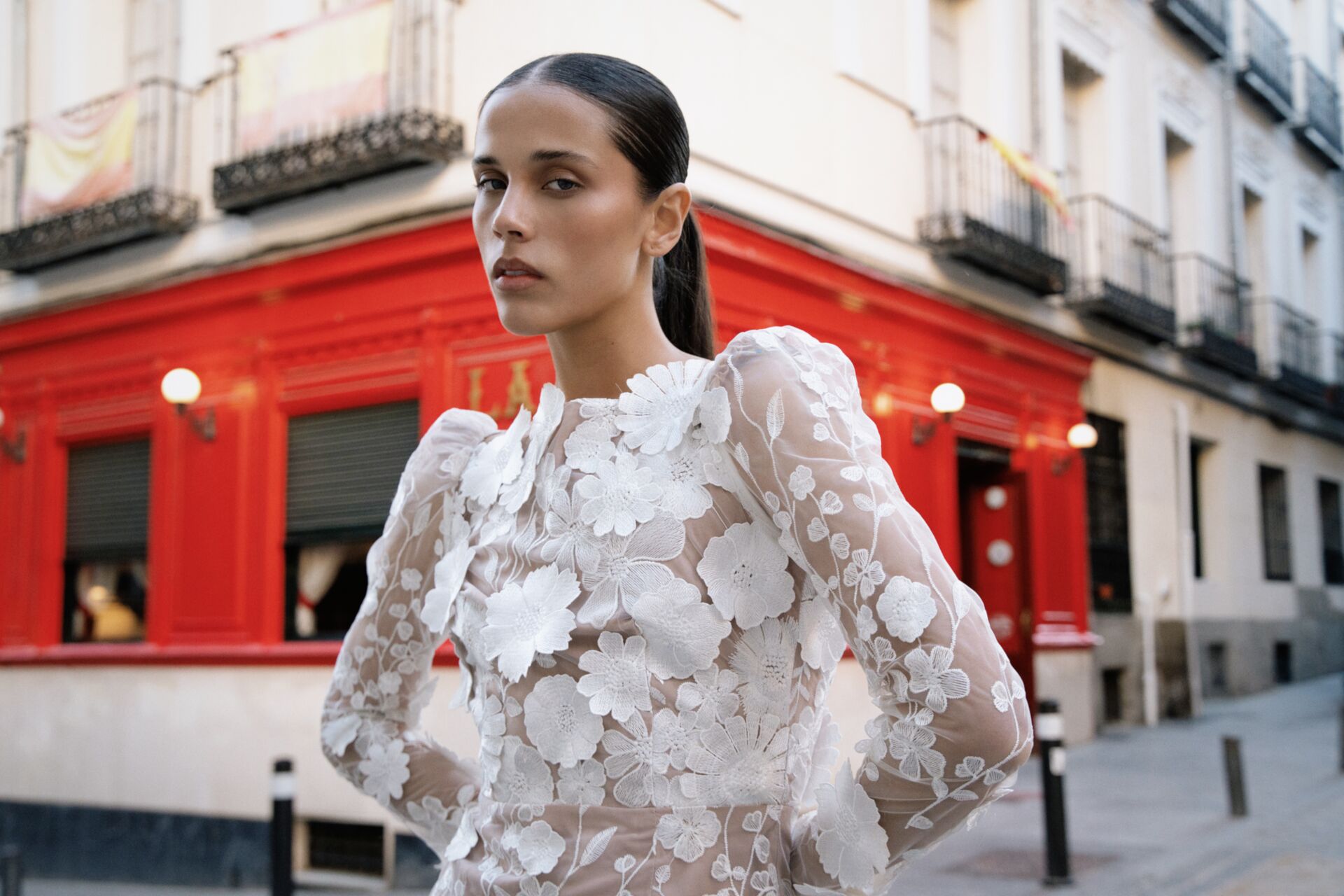 Mujer con vestido de diseñador, edificio rojo al fondo